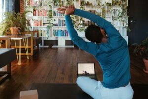 Person gör en sittande sidosträckning framför en laptop hemma